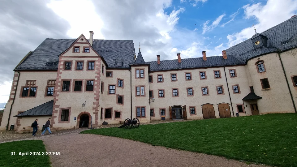 Ein großes Gebäude mit Rasen und einer Kanone davor